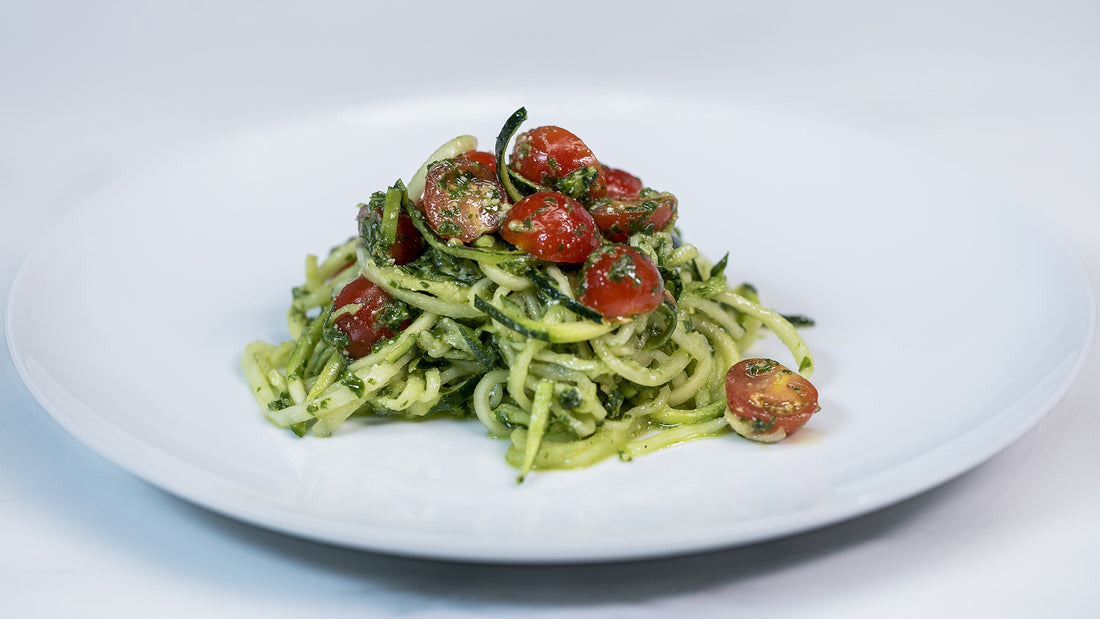 Pesto Zucchini Noodles with tomatoes on a white plate